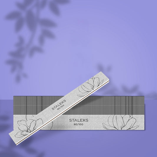 Set de 25 de pile minerale drepte STALEKS EXPERT 20, granulație 80/100 pentru gel și acril, cu o pilă albă așezată oblic pe fundal mov.