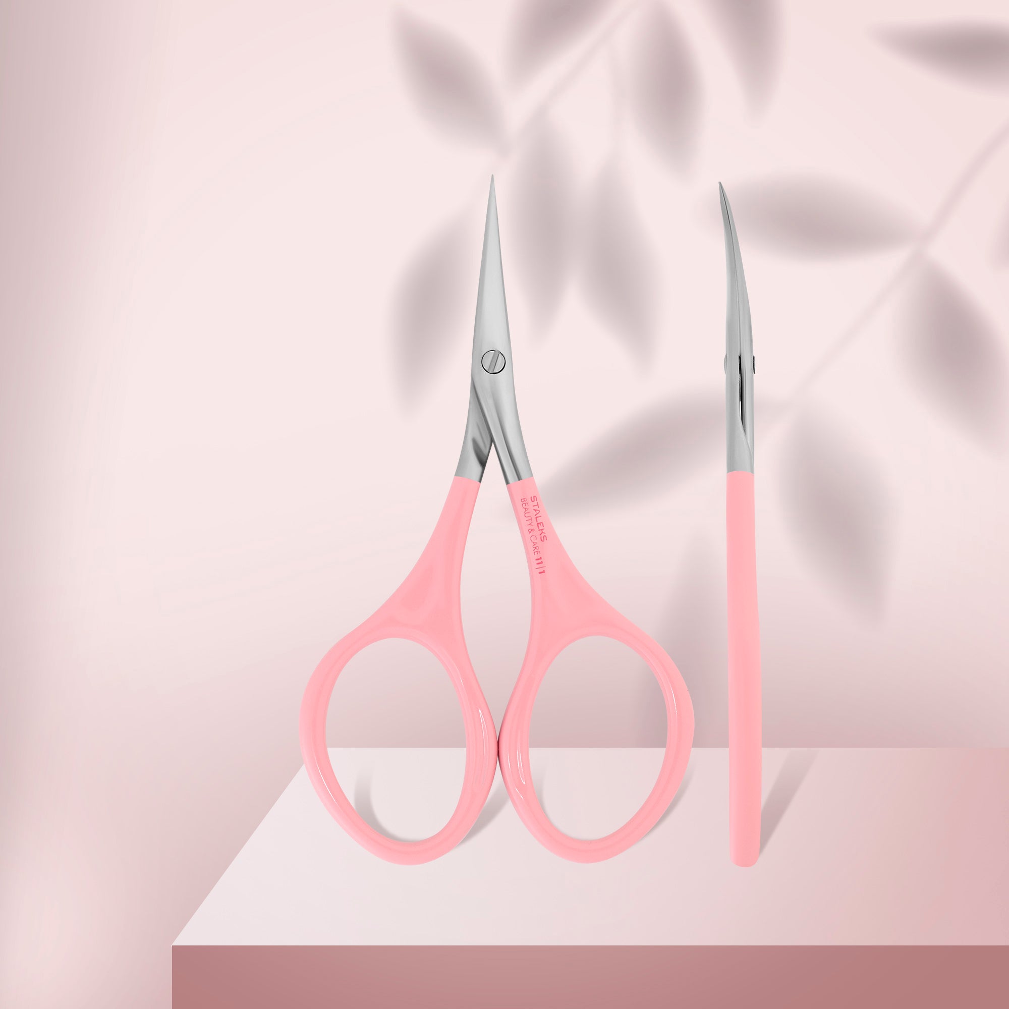 Forfecuță pentru cuticule STALEKS BEAUTY & CARE 11 TYPE 1 SBC-11/1, cu mânere roz și inele mărite, prezentată din față și lateral pe fundal roz.