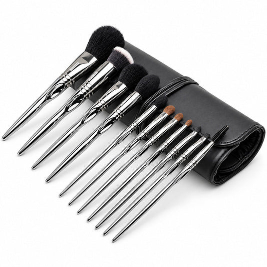 Set 11 pensule profesionale de machiaj Silver Touch, cu mânere argintii, așezate oblic lângă accesoriul negru rulat.